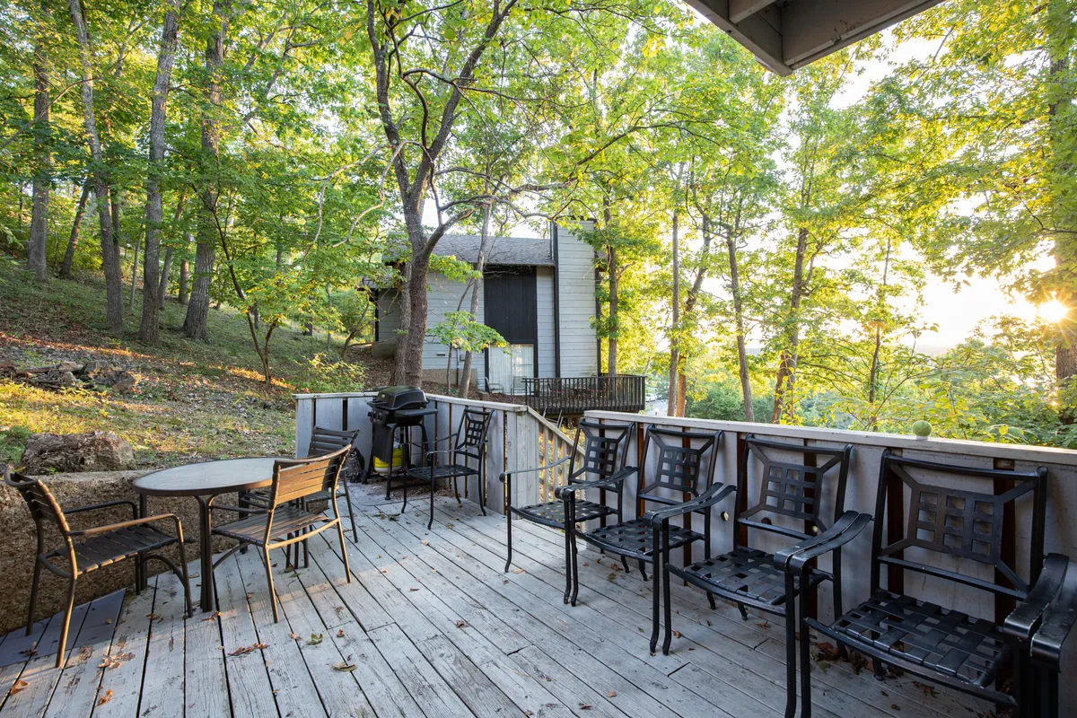 A welcoming wooden deck with ample outdoor seating, a grill, and forested surroundings. The setting is ideal for hosting barbecues, enjoying meals outside, or simply absorbing the natural beauty in a serene atmosphere.