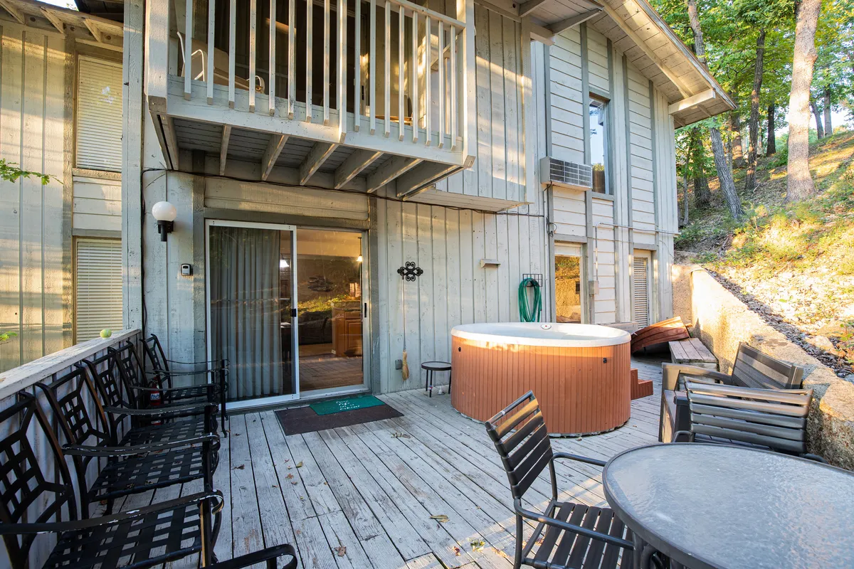 A wooden deck with a bubbling hot tub and comfortable outdoor seating offers a relaxing retreat with scenic views. The setting is ideal for unwinding after a day of activities, whether soaking in the hot tub under the stars or gathering with friends for evening chats.