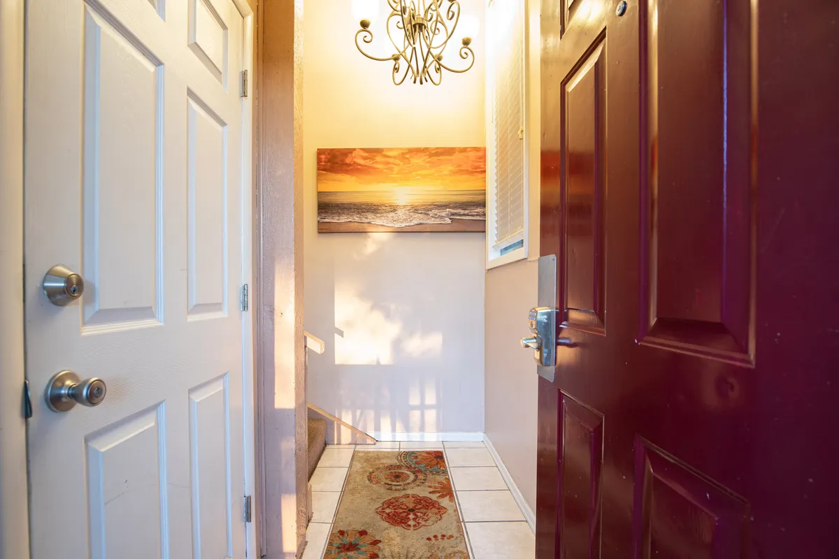 A welcoming view of the entryway, featuring an inviting front door, a stylish chandelier, and tasteful wall art. The space is well-lit, with a rug creating a cozy and cared-for first impression as you step inside.