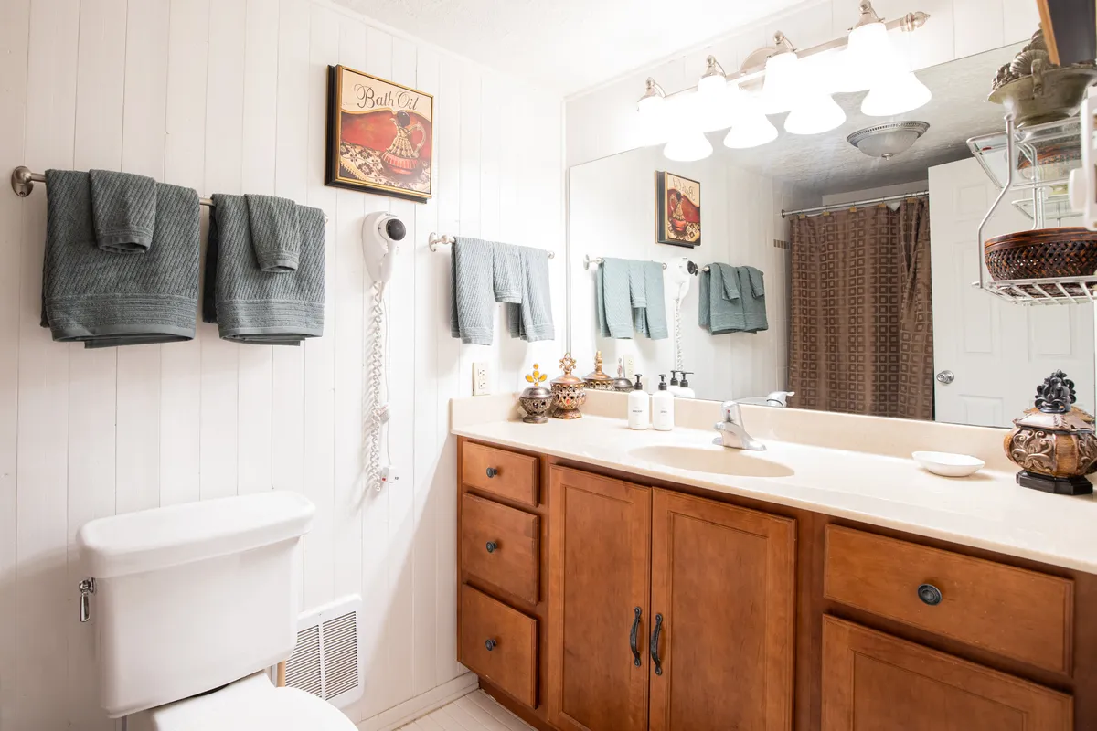 A clean, organized bathroom vanity with fluffy towels, decorative items, and framed wall art. The calm and organized setting is ideal for personal routines and underscores the retreat’s attention to detail.